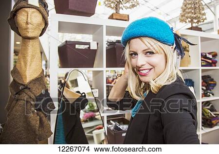 Picture - Young woman trying on hats in the mall; St. Albert, Alberta, Canada. Fotosearch