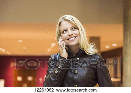 Stock Image - Young woman using smart phone in shopping complex; St. Albert, Alberta, Canada. Fotosearch