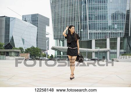 Stock Photo - Young woman walking in business district; Xiamen, China. Fotosearch