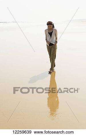 Stock Photo - Young woman walking on the beach from HuoHu, North of Kinmen Island; Taiwan. Fotosearch