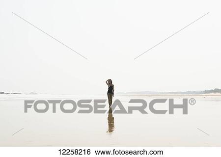 Stock Photograph - Young woman walking on the beach from HuoHu, North of Kinmen Island; Taiwan. Fotosearch