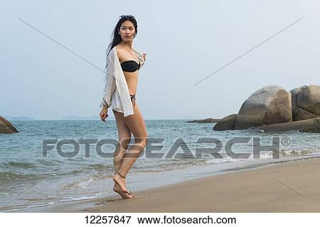 Young woman walking on the beach in a bikini; Xiamen, China View Large Photo Image Stock Photo - Young woman walking on the beach in a bikini; Xiamen, China. Fotosearch
