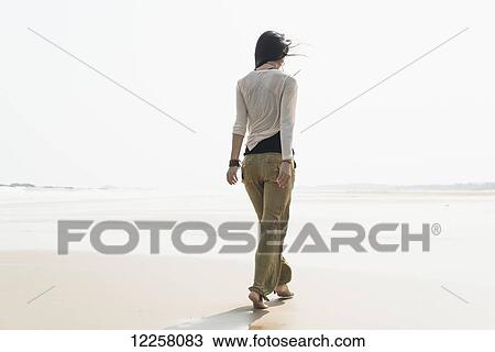 Stock Image - Young woman walking on the beach; Huohu, Taiwan. Fotosearch