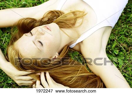 Stock Photo - Young Woman With Freckles And Red Hair Lays In The Grass.. Fotosearch