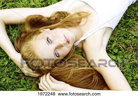 Stock Photo - Young Woman With Freckles And Red Hair Lays In The Grass And Looks Up.. Fotosearch