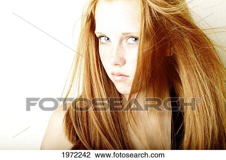 Stock Image - Young Woman With Red Hair And Freckles Glances Out Of The Corner Of Her Eye.. Fotosearch