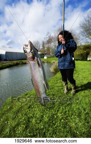 Stock Photograph - Young Women At A Fish Farm Catching Trout With A Fishing Rod; Vale Of The White Horse, Oxfordshire, Uk. Fotosearch
