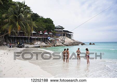 Stock Photo - Young women in bikinis talking on a white sand beach; Ko Phangan, Thailand. Fotosearch
