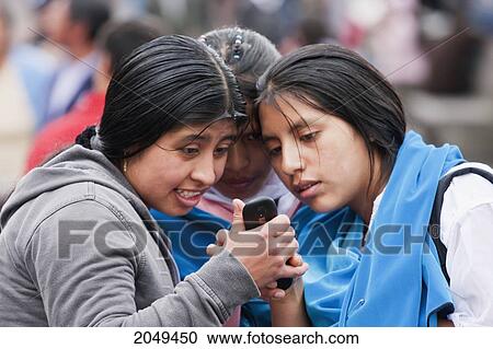 Stock Image - Young Women Watching A Mobile Phone On Plaza Grande, Quito, Pichincha, Ecuador. Fotosearch
