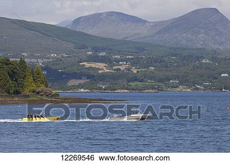 A boat pulls an inflatable banana ride in the lake; Kenmare, County Kerry, Ireland View Large Photo Image Stock Photograph - A boat pulls an inflatable banana ride in the lake; Kenmare, County Kerry, Ireland. Fotosearch
