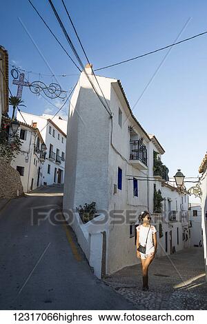 Stock Photograph - A Chinese young woman walking on the street of the beautiful town of Altea in Costa Blanca; Altea, Alicante, Spain. Fotosearch