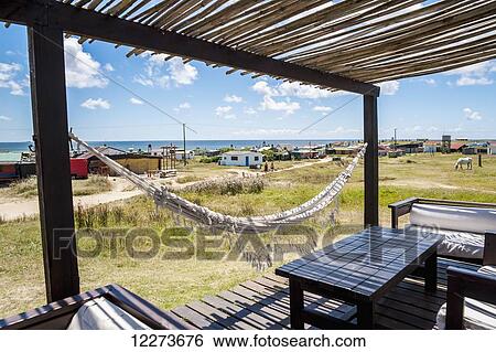 A covered porch with furniture and a hammock, and numerous buildings along the coast; Cabo Polonio, Uruguay View Large Photo Image Stock Photograph - A covered porch with furniture and a hammock, and numerous buildings along the coast; Cabo Polonio, Uruguay. Fotosearch