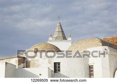 Stock Photography - A cross atop a peaked colourful rooftop; Cadiz, Andalusia, Spain. Fotosearch