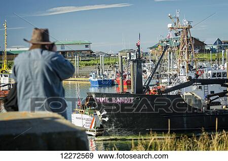Stock Photo - A cruise ship passenger photographs the F/V Time Bandit at the Homer harbor, Southcentral Alaska, Autumn. Fotosearch