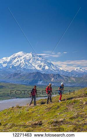 Stock Image - A family of three are hiking up a trail near the Eielson Visitor Center in Denali National Park with Mt. McKinley in the background, Interior Alaska. Fotosearch