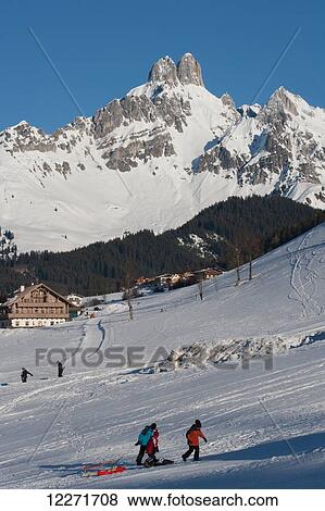 A family pull sleds at the ski resort in the Austrian Alps with the Bishop's Hat mountain peaks behind; Filzmoos, Austria View Large Photo Image Stock Photo - A family pull sleds at the ski resort in the Austrian Alps with the Bishop's Hat mountain peaks behind; Filzmoos, Austria. Fotosearch
