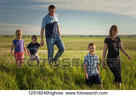 Stock Photograph - A family walks through a farm field; Herschel, Saskatchewan, Canada. Fotosearch