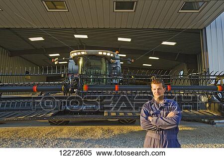 A farmer next to his combine parked in front of the farm repair shop, near Lorette; Manitoba, Canada View Large Photo Image Stock Photography - A farmer next to his combine parked in front of the farm repair shop, near Lorette; Manitoba, Canada . Fotosearch