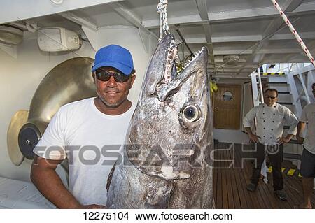 Picture - A fisherman poses with a dogtooth tuna (Gymnosarda unicolor); Tahiti. Fotosearch