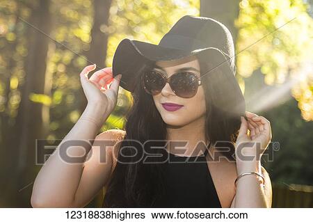 A fun and fashion forward teenage girl poses away from the sun with sunglasses and a designer hat to protect her pale shoulders as she holds her hat to shield from the sun; Vancouver, British Columbia, Canada View Large Photo Image Stock Photograph - A fun and fashion forward teenage girl poses away from the sun with sunglasses and a designer hat to protect her pale shoulders as she holds her hat to shield from the sun; Vancouver, British Columbia, Canada. Fotosearch
