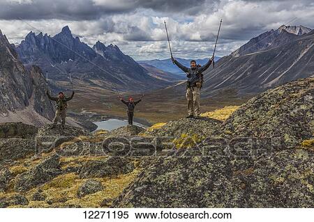 Stock Photography - A group of hikers standing on rocks overlooking the colourful valleys in Tombstone Territorial Park in autumn; Yukon, Canada. Fotosearch