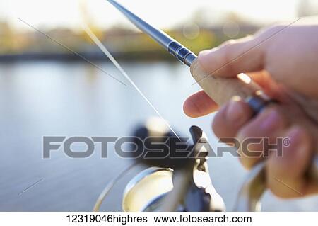A hand holding a fishing rod and holding it out over the water; Quebec, Canada View Large Photo Image Stock Photograph - A hand holding a fishing rod and holding it out over the water; Quebec, Canada. Fotosearch