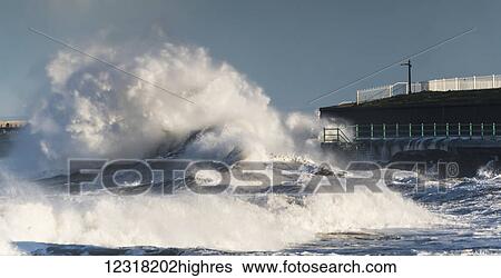 Stock Photograph - A large wave breaks and crashes against the shore; Sunderland, Tyne and Wear, England. Fotosearch