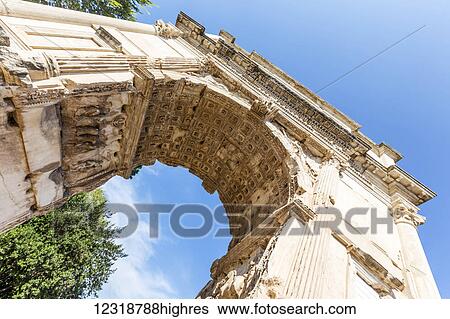 Stock Photograph - A low angle view of the historic Arch of Titus near the Roman Forum dating back to 81 AD; Rome, Italy. Fotosearch