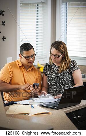 A man and woman in the kitchen working together with documents and a computer; Regina, Saskatchewan, Canada View Large Photo Image Stock Photograph - A man and woman in the kitchen working together with documents and a computer; Regina, Saskatchewan, Canada. Fotosearch