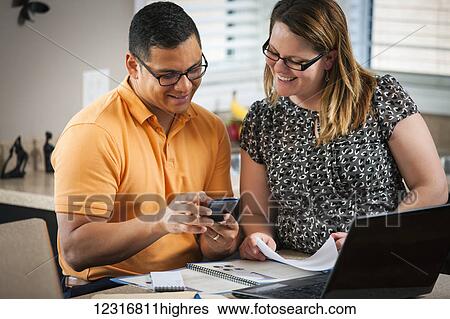 A man and woman in the kitchen working together with documents and a computer; Regina, Saskatchewan, Canada View Large Photo Image Stock Photograph - A man and woman in the kitchen working together with documents and a computer; Regina, Saskatchewan, Canada. Fotosearch