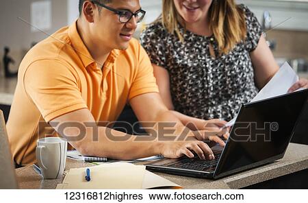 A man and woman in the kitchen working together with documents and a computer; Regina, Saskatchewan, Canada View Large Photo Image Stock Photograph - A man and woman in the kitchen working together with documents and a computer; Regina, Saskatchewan, Canada. Fotosearch