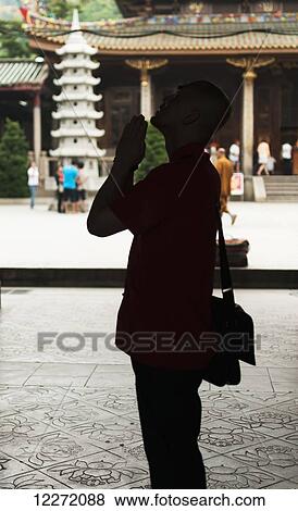 Stock Photo - A man praying in Nan Pu Tuo buddhist temple; Xiamen, Fujian Province, China. Fotosearch