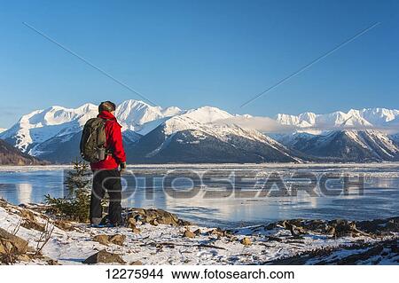 Picture - A man snowshoeing along the Cook Inlet with Kenai Mountains in the background, Southcentral Alaska, Winter. Fotosearch