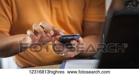 Stock Photograph - A man typing on his smart phone; Regina, Saskatchewan, Canada. Fotosearch