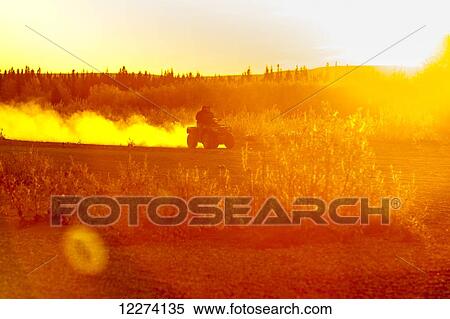 A native Alaskan drives an ATV down a dusty road on the banks of the Noatak River at sunset, Noatak, Arctic Alaska, USA View Large Photo Image Stock Photography - A native Alaskan drives an ATV down a dusty road on the banks of the Noatak River at sunset, Noatak, Arctic Alaska, USA. Fotosearch