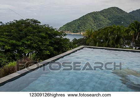 Stock Photograph - A pool of water with a view of the coastline and lush foliage; Jalisco, Mexico. Fotosearch