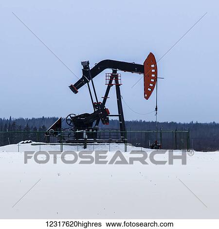 Stock Photograph - A pumpjack in a field covered in snow; Alberta, Canada. Fotosearch