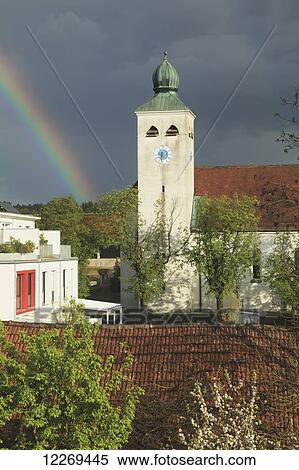 Stock Photography - A rainbow beside a clock tower; Gilching, Bayern, Germany. Fotosearch