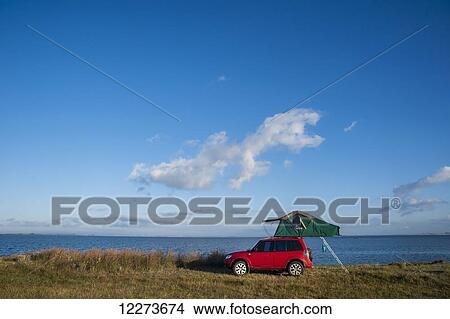 A red vehicle with elevated tent along the coast; Laguna de Rocha, Uruguay View Large Photo Image Picture - A red vehicle with elevated tent along the coast; Laguna de Rocha, Uruguay. Fotosearch
