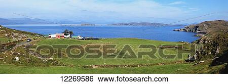 Stock Photograph - A road and houses along the coast, near Eyeries on the Beara Peninsula; County Cork, Ireland. Fotosearch