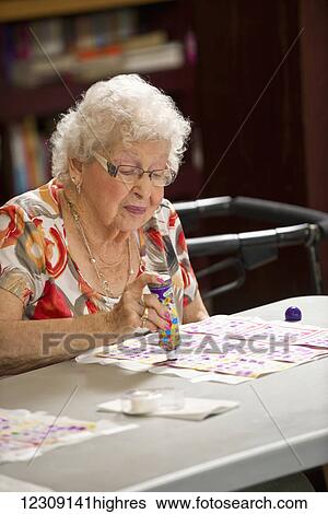 Stock Photograph - A senior woman playing bingo; Devon, Alberta, Canada. Fotosearch