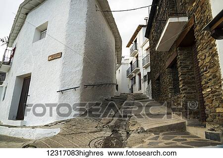 Stock Photograph - A sloped street between houses in Pampaneira, one of the most famous villages in Alpujarra; Granada Province, Andalucia, Spain. Fotosearch