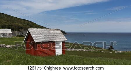 Stock Photograph - A small red shed on a grass hillside overlooking the ocean; Capstick, Nova Scotia, Canada. Fotosearch