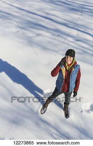 A smiling young woman wearing a hat and gloves stands in a snowbank and talks on her cell phone, Winter, Southcentral Alaska, USA View Large Photo Image Stock Photography - A smiling young woman wearing a hat and gloves stands in a snowbank and talks on her cell phone, Winter, Southcentral Alaska, USA. Fotosearch