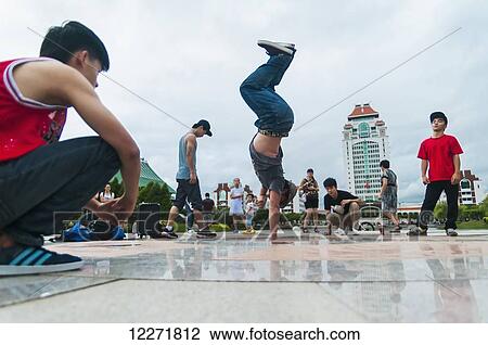Stock Image - A street dancer doing acrobatics next to Xiamen University's lake; Xiamen, Fujian Province, China. Fotosearch