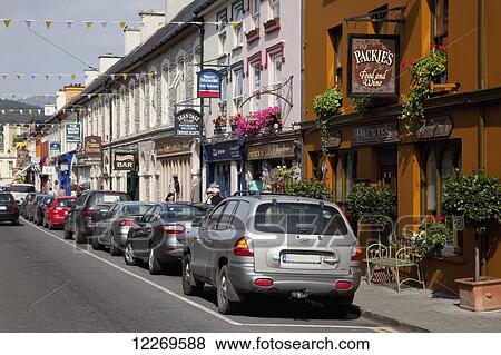Stock Photo - A street lined with parked cars and retail shops; Kenmare, County Kerry, Ireland. Fotosearch