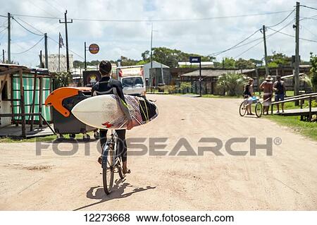 A surfer cycles down a dirt road on his bicycle holding his surfboard; Valizas, Uruguay View Large Photo Image Stock Photo - A surfer cycles down a dirt road on his bicycle holding his surfboard; Valizas, Uruguay. Fotosearch