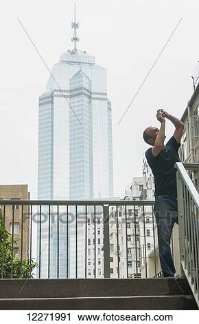 Stock Image - A tourist taking a picture; Hong Kong, China. Fotosearch