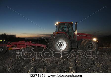 A tractor pulling a disk ripper at dusk tills a field of corn stalks and residue after the harvest, preparing the field for the winter fallow period, near Northrop; Minnesota, United States of America View Large Photo Image Stock Photograph - A tractor pulling a disk ripper at dusk tills a field of corn stalks and residue after the harvest, preparing the field for the winter fallow period, near Northrop; Minnesota, United States of America. Fotosearch