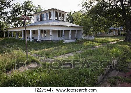 Stock Photo - A vacant, abandoned house in disrepair with the grass overgrown in the yard; United States of America. Fotosearch